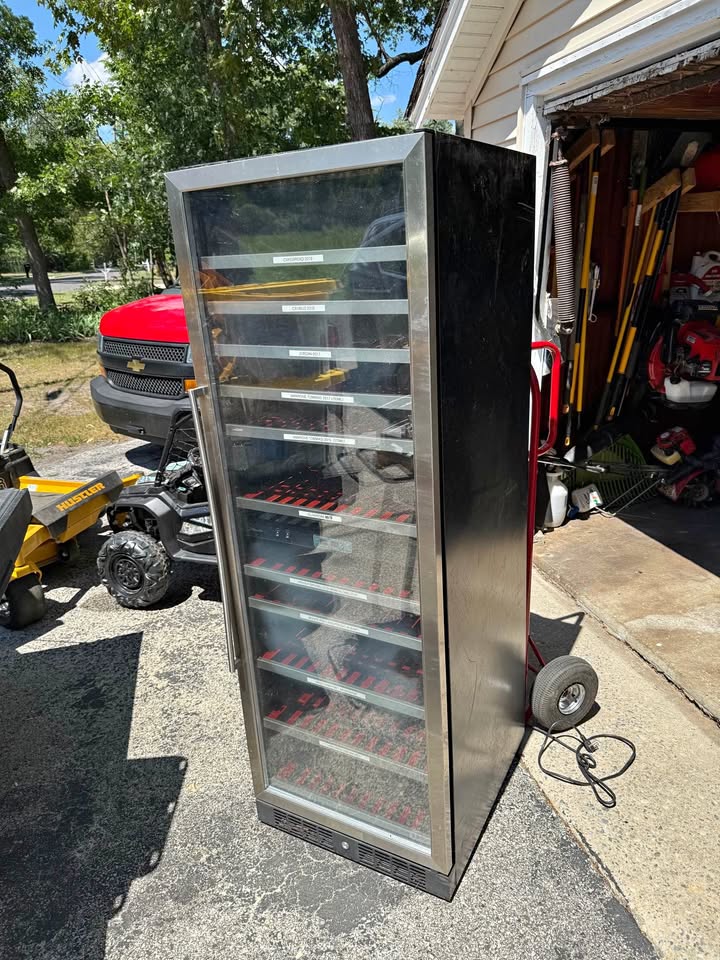 Tall glass-fronted Danby wine cabinet on a hand truck outside a garage before its conversion into the Filament Fridge